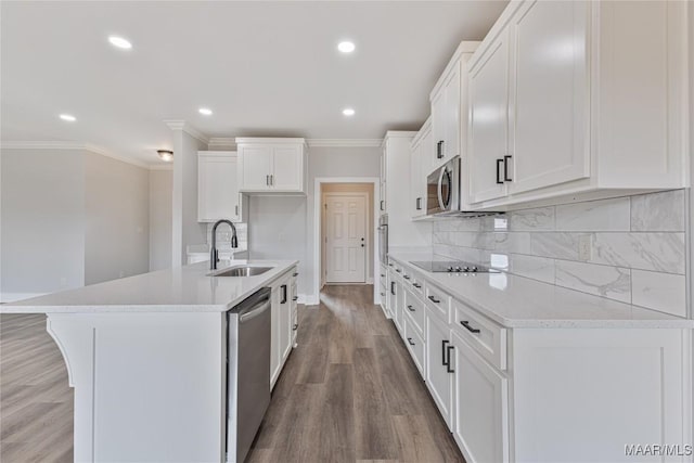 kitchen with stainless steel appliances, sink, wood-type flooring, white cabinets, and an island with sink