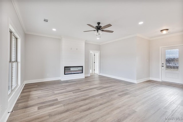 unfurnished living room with ceiling fan, a large fireplace, a healthy amount of sunlight, and light hardwood / wood-style flooring