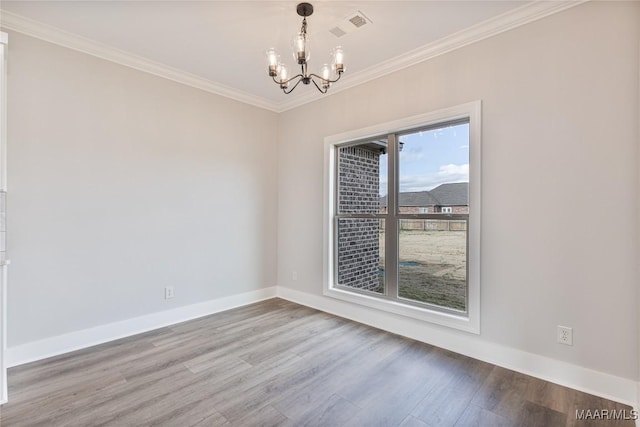 empty room with hardwood / wood-style floors, crown molding, and a chandelier