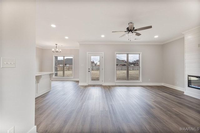 unfurnished living room with ceiling fan with notable chandelier, wood-type flooring, a large fireplace, and crown molding