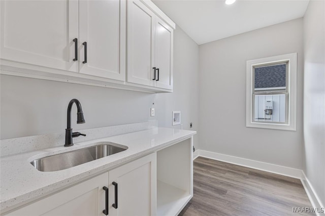 laundry area with electric dryer hookup, cabinets, sink, hookup for a washing machine, and light hardwood / wood-style flooring