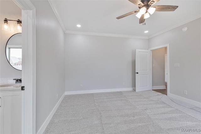 unfurnished room with ceiling fan, light colored carpet, ornamental molding, and sink