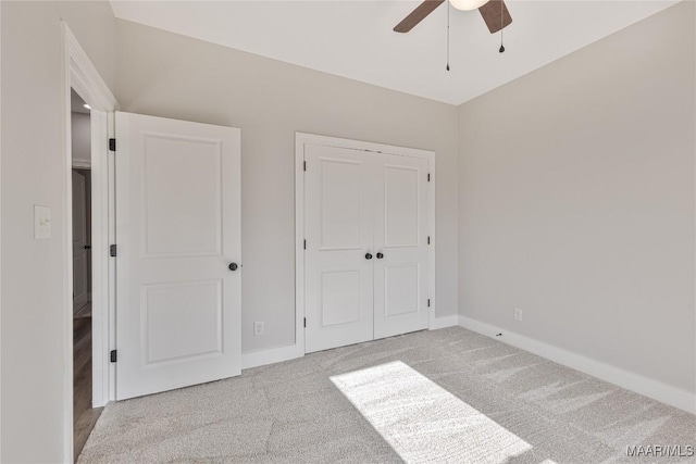 unfurnished bedroom with ceiling fan, light colored carpet, and a closet