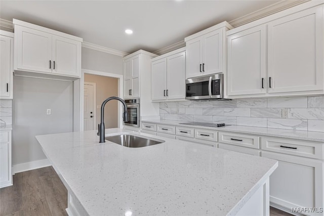 kitchen featuring appliances with stainless steel finishes, tasteful backsplash, a center island with sink, and sink