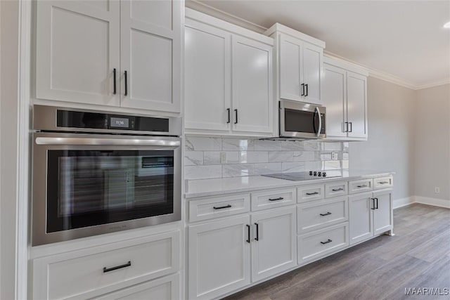 kitchen with appliances with stainless steel finishes, backsplash, light wood-type flooring, crown molding, and white cabinets