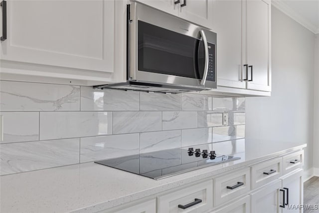 kitchen with white cabinetry, light stone counters, and black electric stovetop