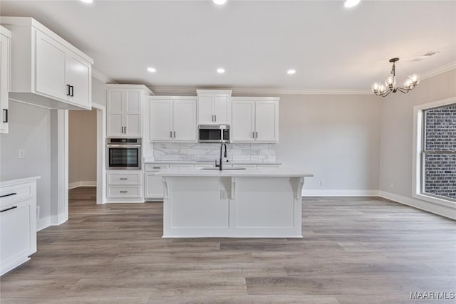 kitchen with sink, stainless steel appliances, tasteful backsplash, a kitchen island with sink, and white cabinets