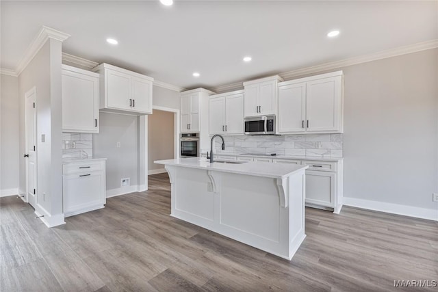 kitchen featuring sink, light wood-type flooring, an island with sink, white cabinetry, and stainless steel appliances