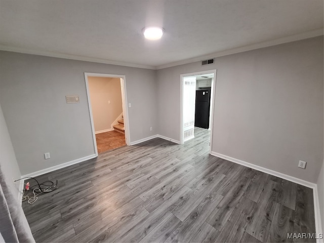 empty room with hardwood / wood-style floors and ornamental molding