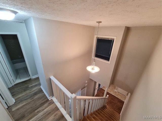 stairs featuring a textured ceiling and wood-type flooring