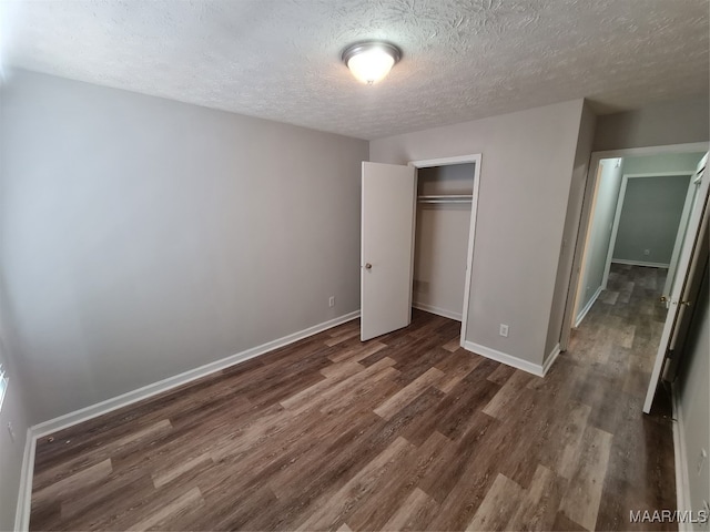 unfurnished bedroom with a textured ceiling, a closet, and hardwood / wood-style flooring