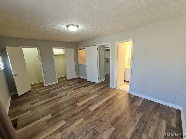 unfurnished bedroom featuring hardwood / wood-style floors, connected bathroom, and a textured ceiling