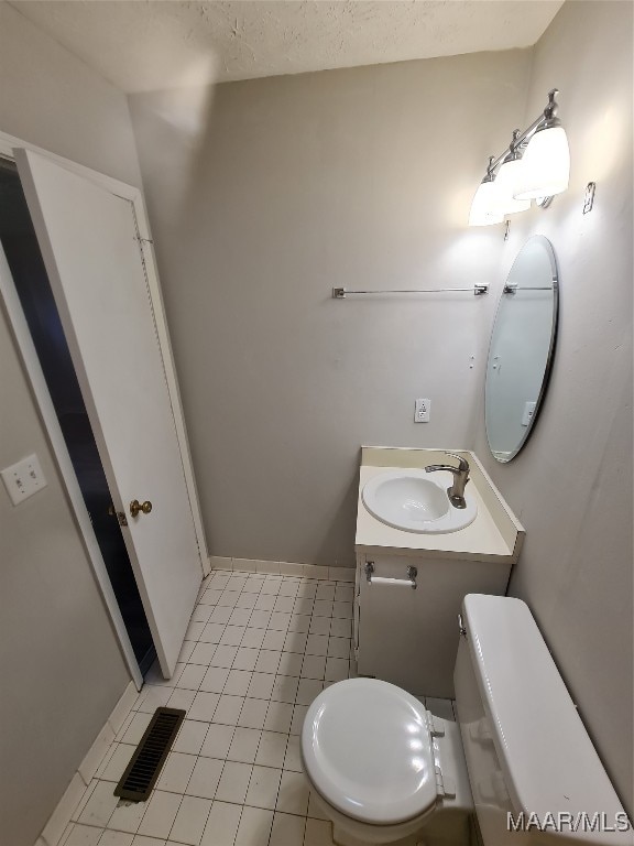 bathroom with toilet, vanity, and tile patterned floors