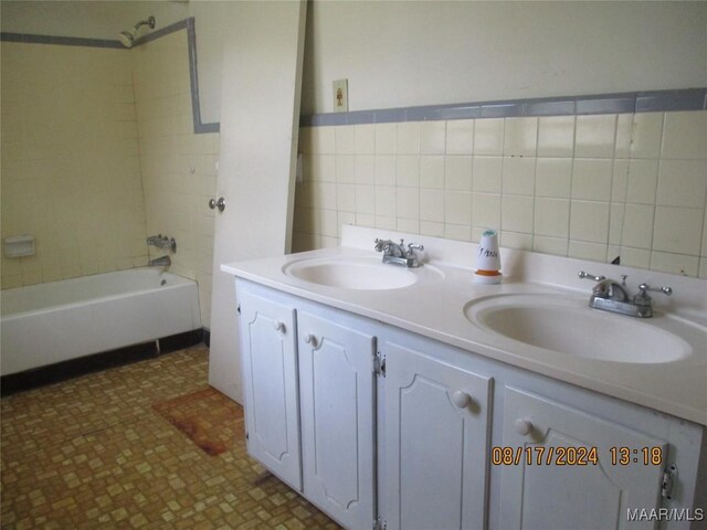 bathroom with tasteful backsplash, tiled shower / bath, dual bowl vanity, and tile patterned floors