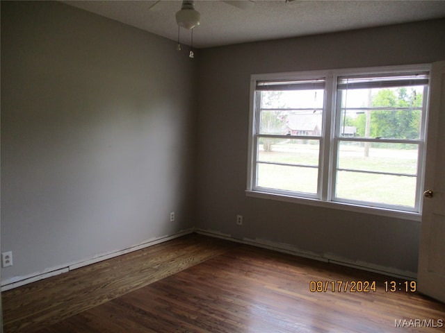 spare room with a wealth of natural light and dark wood-type flooring