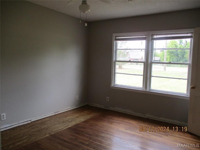 unfurnished room with a healthy amount of sunlight, dark wood-type flooring, and ceiling fan