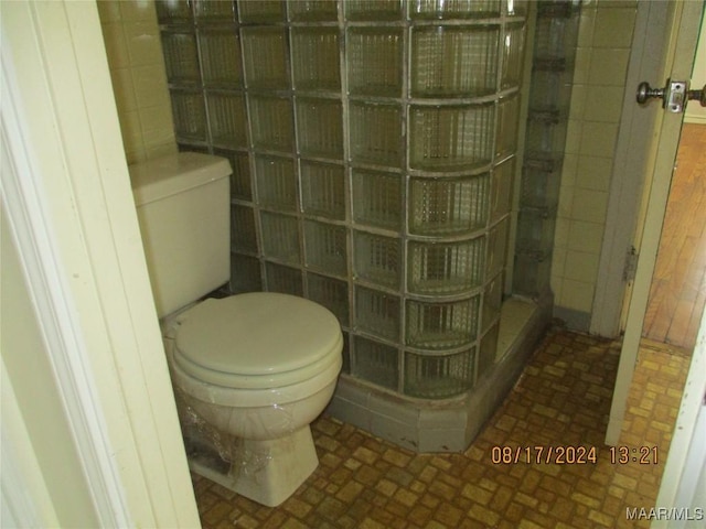 bathroom featuring tile walls, toilet, and walk in shower