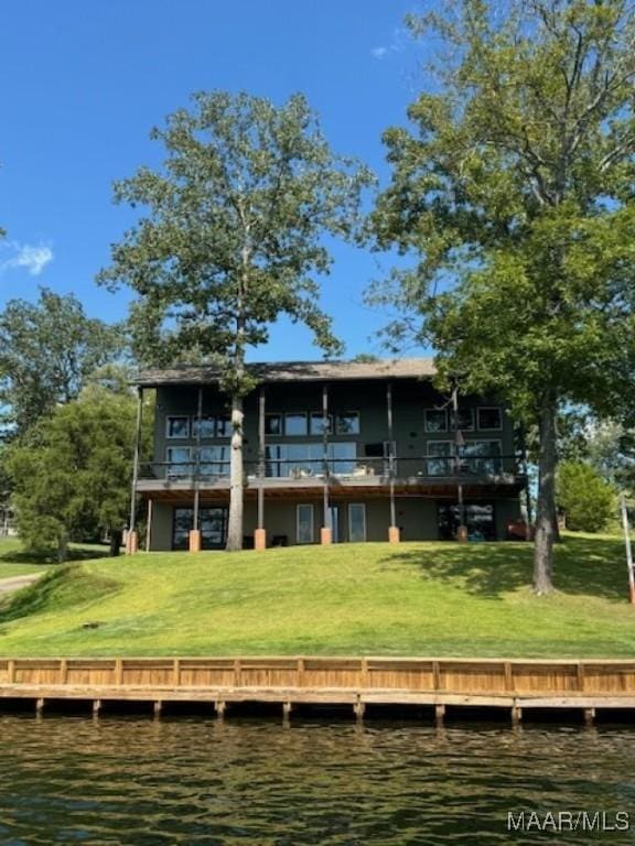 rear view of house with a lawn and a water view