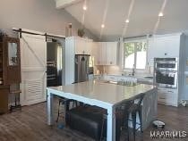 kitchen featuring stainless steel double oven, a breakfast bar, a kitchen island, white cabinets, and light countertops