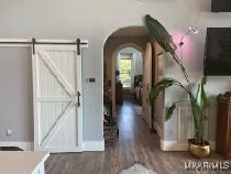 corridor with arched walkways and dark wood finished floors