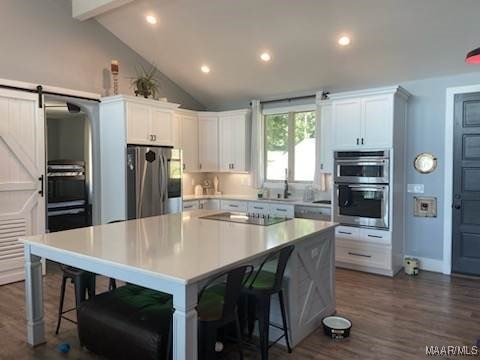 kitchen featuring stainless steel appliances, white cabinets, light countertops, and a barn door