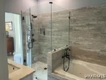 bathroom with a shower stall, vanity, and a bath