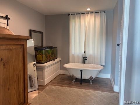 full bathroom featuring a freestanding bath, baseboards, and wood finished floors