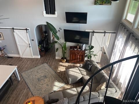 living room with dark wood-type flooring, arched walkways, baseboards, and a barn door