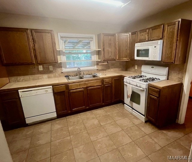 kitchen featuring sink, light tile patterned flooring, and white appliances