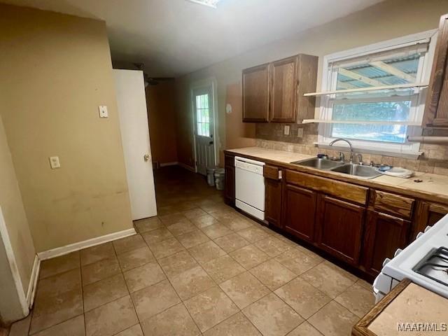 kitchen featuring backsplash, dishwasher, light tile patterned floors, and sink