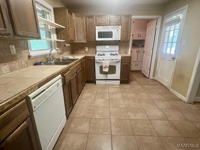 kitchen with sink, white appliances, light tile patterned flooring, and plenty of natural light