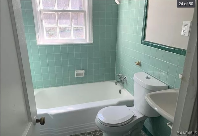 full bathroom with toilet, tile walls, tile patterned floors, sink, and tiled shower / bath