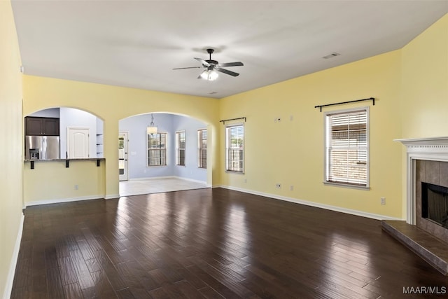 unfurnished living room featuring ceiling fan, wood-type flooring, and a tile fireplace