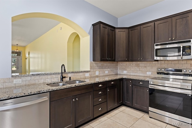 kitchen with appliances with stainless steel finishes, sink, decorative backsplash, and light stone counters