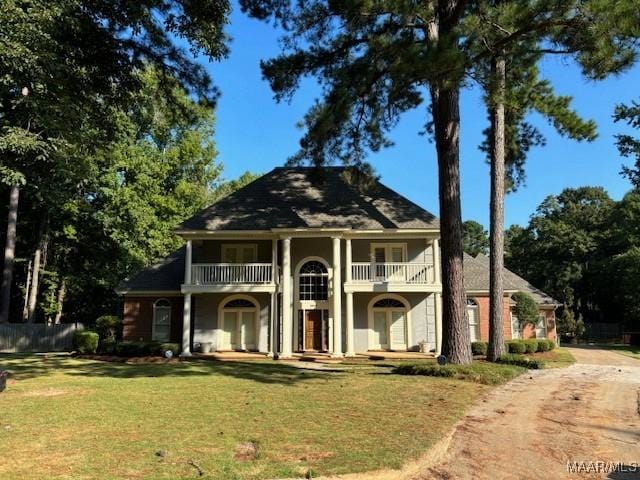 greek revival house featuring driveway, a front lawn, and a balcony