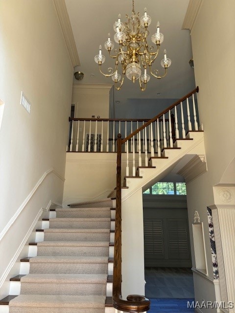 staircase featuring crown molding, a high ceiling, and a notable chandelier