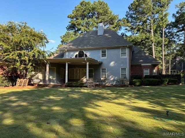 rear view of property featuring a chimney and a lawn