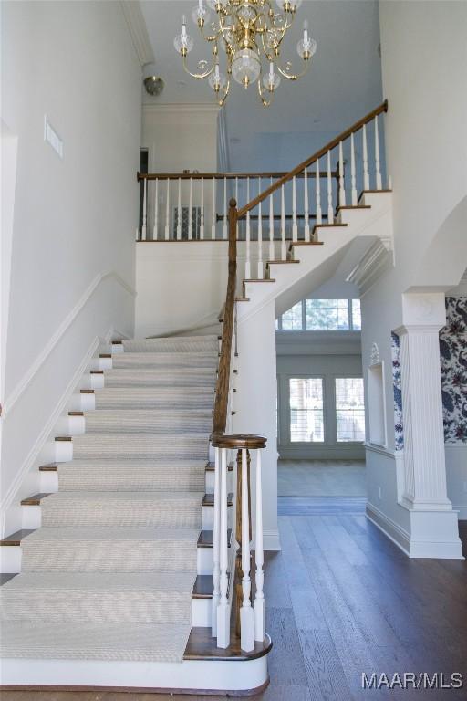 stairway featuring ornamental molding, baseboards, a high ceiling, and wood finished floors