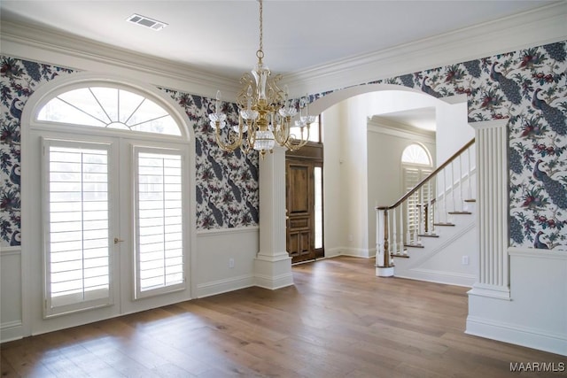 interior space featuring wallpapered walls, visible vents, wainscoting, wood finished floors, and stairs