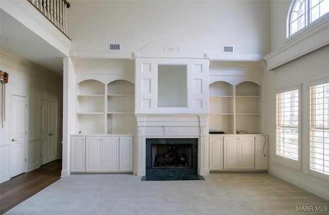 unfurnished living room featuring a towering ceiling, visible vents, and built in features