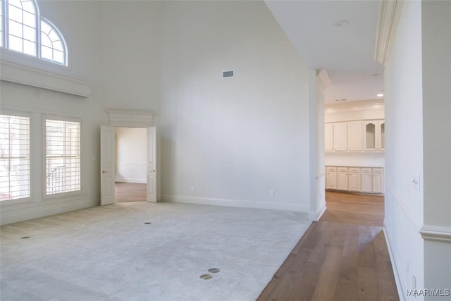 interior space with a towering ceiling, baseboards, visible vents, and wood finished floors