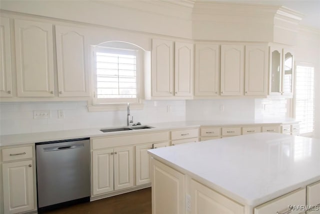 kitchen with a sink, white cabinets, stainless steel dishwasher, a center island, and crown molding