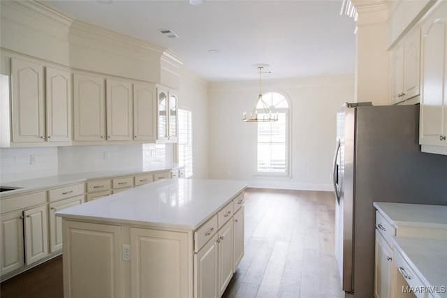 kitchen with light countertops, visible vents, crown molding, and backsplash