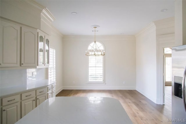 dining space with a chandelier, baseboards, light wood-style flooring, and crown molding