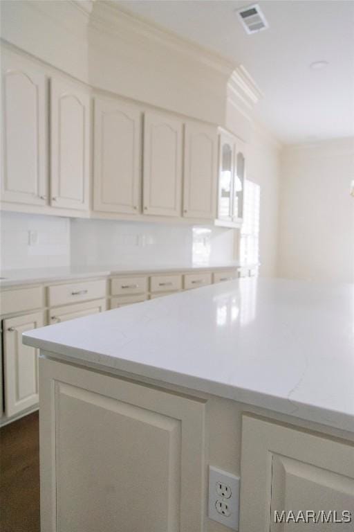 kitchen featuring ornamental molding, white cabinetry, visible vents, and light stone countertops