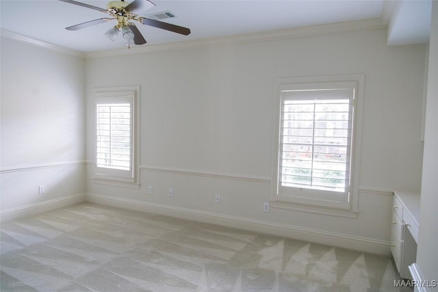 unfurnished room with a ceiling fan, light carpet, crown molding, and baseboards