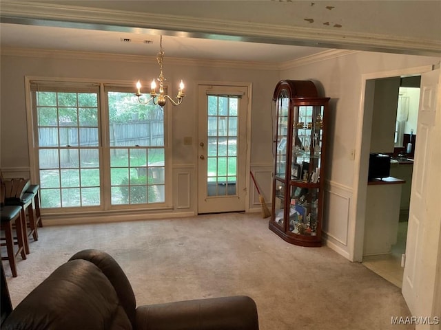 entryway with an inviting chandelier, a decorative wall, wainscoting, carpet, and ornamental molding