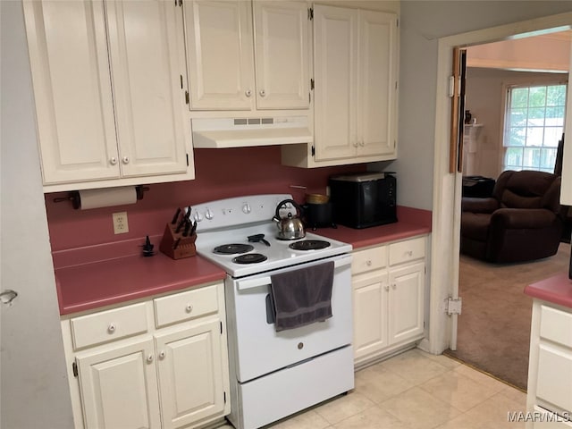 kitchen with custom exhaust hood, white range with electric cooktop, white cabinets, and light carpet