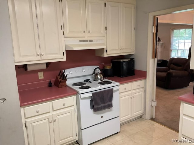kitchen featuring light tile patterned floors, electric range, under cabinet range hood, light carpet, and white cabinetry