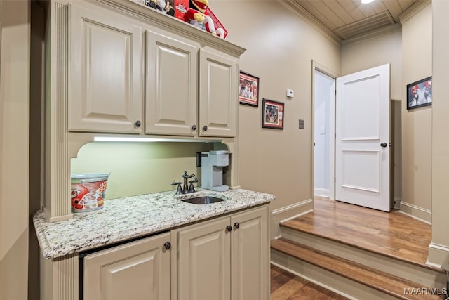 kitchen featuring sink, light stone counters, crown molding, and wood-type flooring